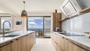 Una cocina moderna con armarios de madera, una isla grande y vistas al océano.