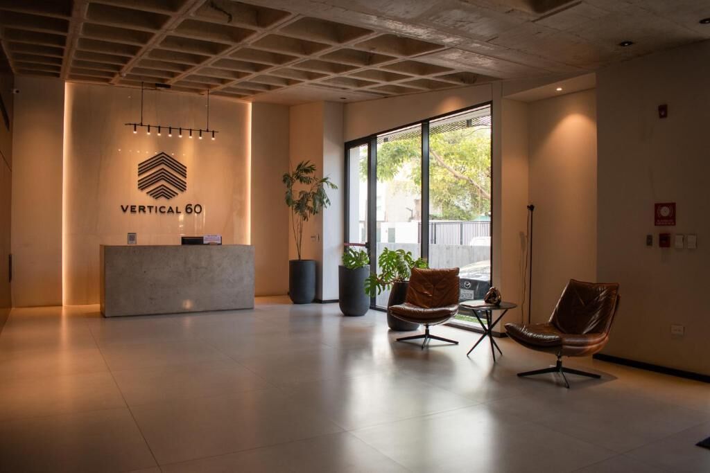 A reception area with a reception desk, two leather chairs, potted plants, and a large window providing a view outside.