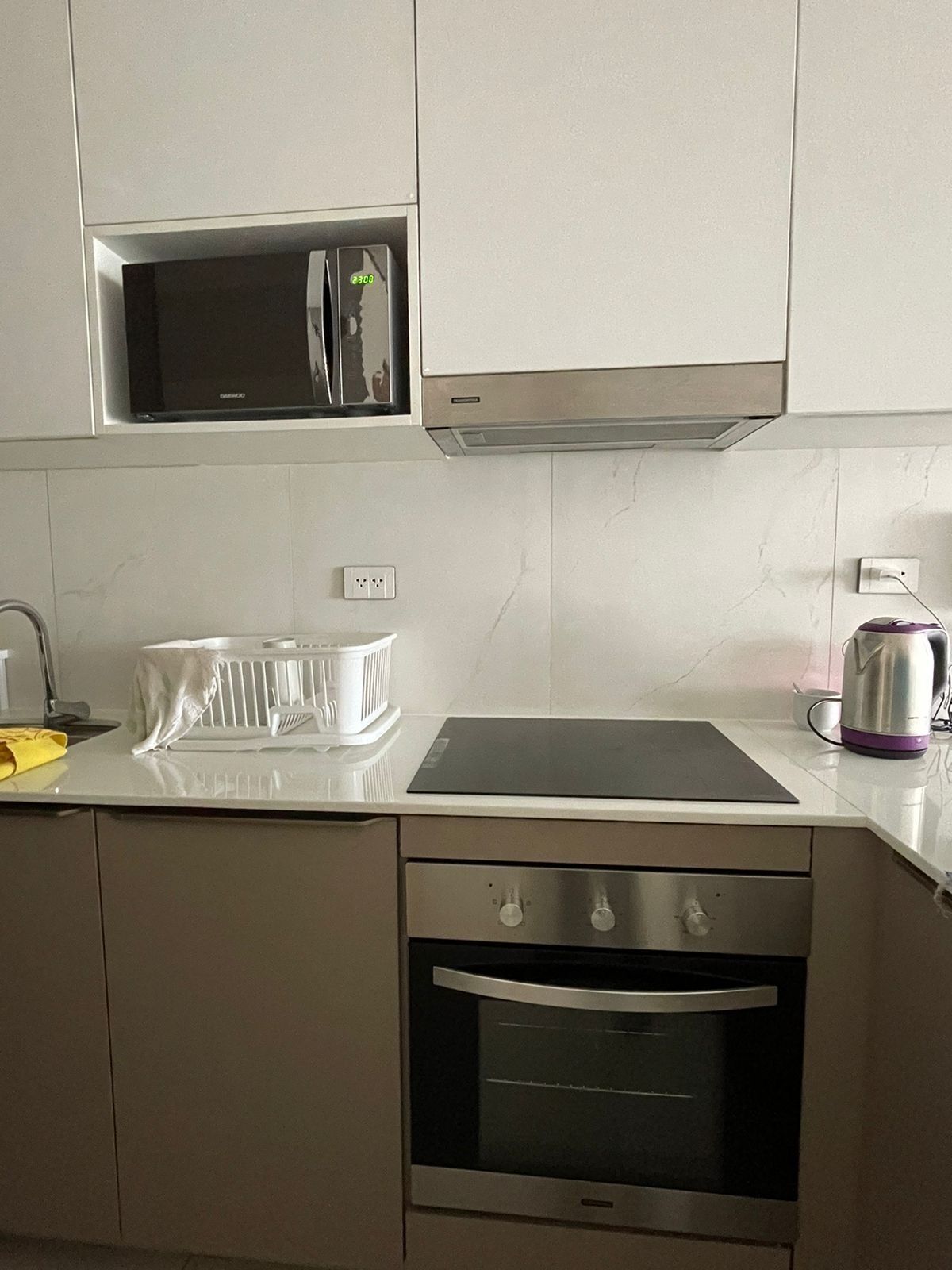 A kitchen with a microwave, oven, and a kettle on the counter.