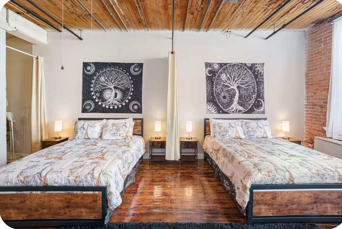 A double bed room with a wooden ceiling, two nightstands, and two wall-mounted lamps.