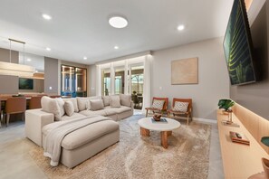 Ein modernes Wohnzimmer mit einem Ecksofa, einem Couchtisch und einem an der Wand montierten Fernseher.