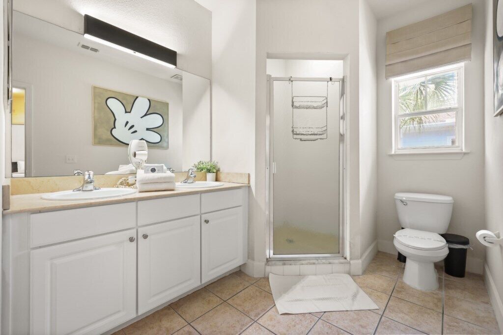 Un baño con ducha, inodoro, lavabo y perchero para toallas.