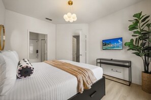 A bedroom with a bed, bedside table, TV, and a large plant. - 4 BD/ 3 BA/ Lucaya Village (6-105) (Kissimmee)