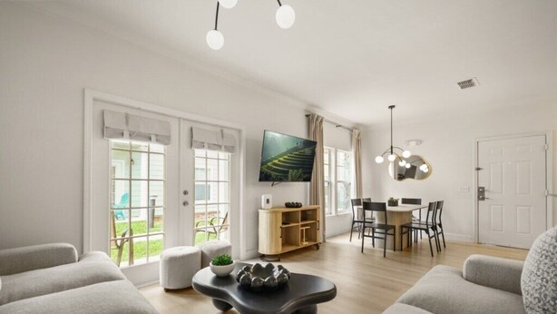 Uma sala de estar moderna com sofá, mesa de centro, TV e um canto de jantar com cadeiras e mesa.