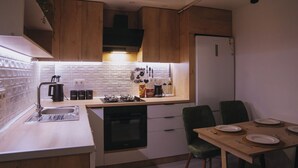 Una cocina compacta con armarios de madera, estufa integrada, un lavamanos y un comedor con mesa dispuesta para cuatro.