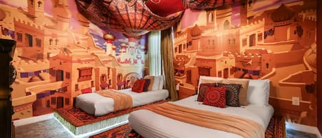 A room with a bed, two bedside tables, and a chandelier.