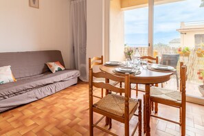 Una habitación con sofá, mesa de comedor, sillas y vista al mar.
