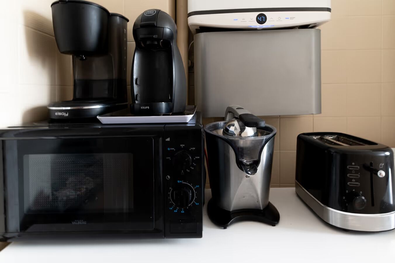 A kitchen with a microwave, coffee maker, toaster, and a kettle.