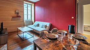Un salon moderne avec un plancher en bois, un canapé, une table basse et une table à manger dressée avec des assiettes et des verres.
