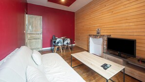 Un salon moderne avec un mur rouge, un lambris en bois, un canapé blanc, une table basse, un téléviseur et une cheminée.