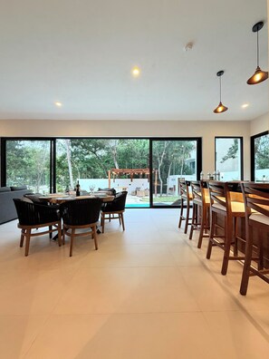 A modern dining area with a large window, a dining table, and chairs. - Your luxury hideaway with private pool and perfect location in Riviera Maya (Puerto Morelos)