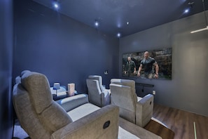 A home theater room with two reclining chairs, a popcorn container, and a large movie poster on the wall. - Vista Cay Retreat: Stunning 3-Level Townhome/ 3 BD/ 3.5  BA (5076-90 TC) (Orlando)