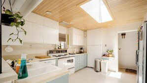 A modern kitchen with white cabinets, a stove, a sink, and a window. - An updated mid-century modern house in one of Boulder's best neighborhoods. (Boulder)
