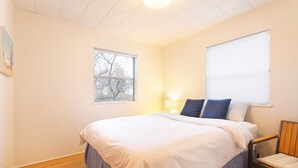 A bedroom with a bed, a window, a lamp, and a chair. - An updated mid-century modern house in one of Boulder's best neighborhoods. (Boulder)
