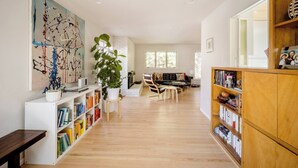 A spacious living area with a bookshelf, a sofa, a coffee table, and a large plant. - An updated mid-century modern house in one of Boulder's best neighborhoods. (Boulder)