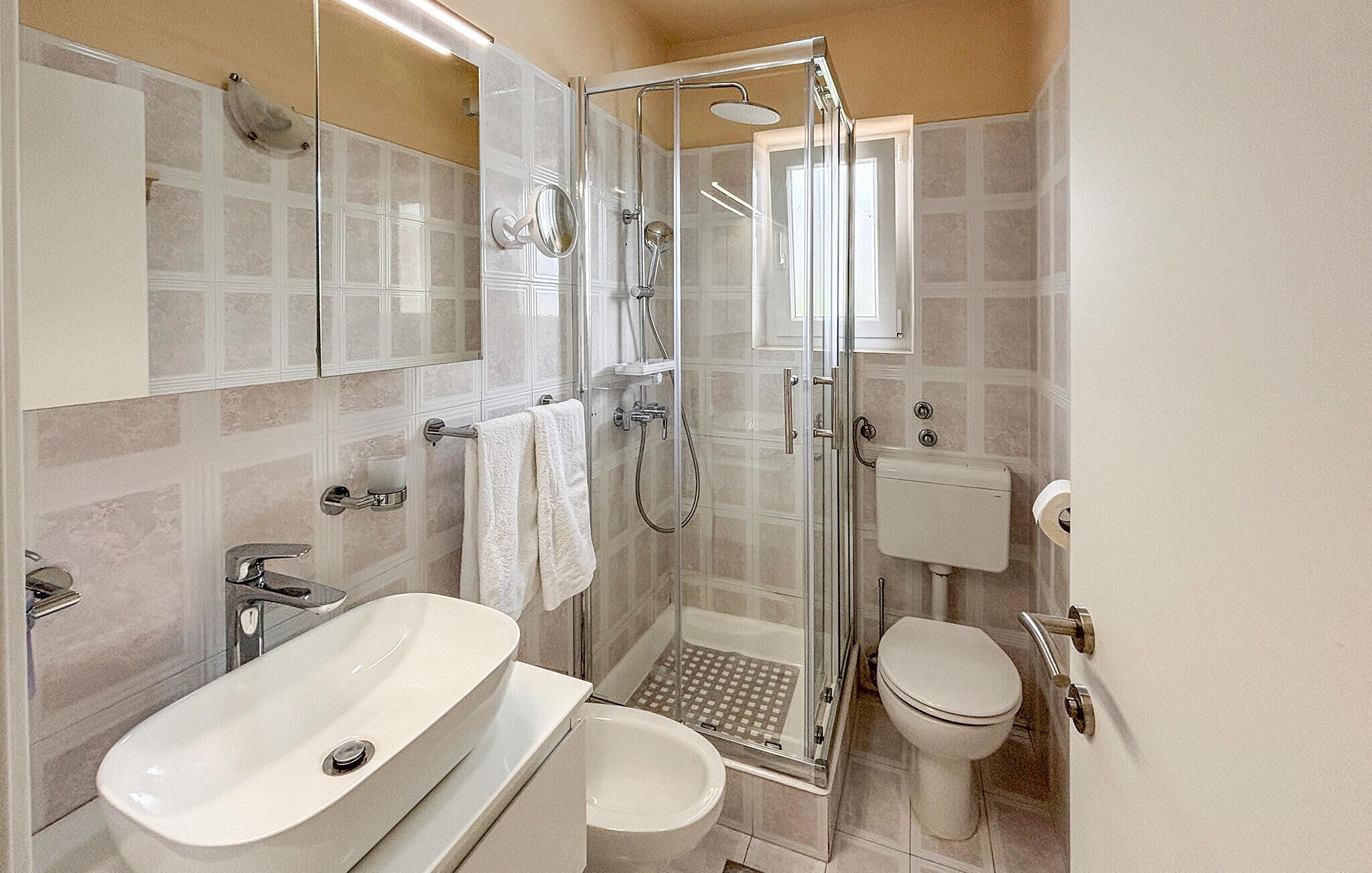 A modern bathroom with a glass-enclosed shower, a freestanding bathtub, a toilet, and a sink.
