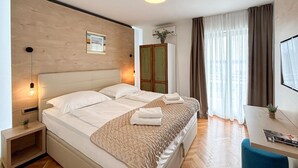 A hotel room with a bed, bedside tables, a desk, and a wardrobe. - Cozy apartment in Omisalj with WiFi (Omisalj)