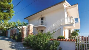 A two-story house with a balcony, a gated entrance, and a small garden. - Cozy apartment in Omisalj with WiFi (Omisalj)