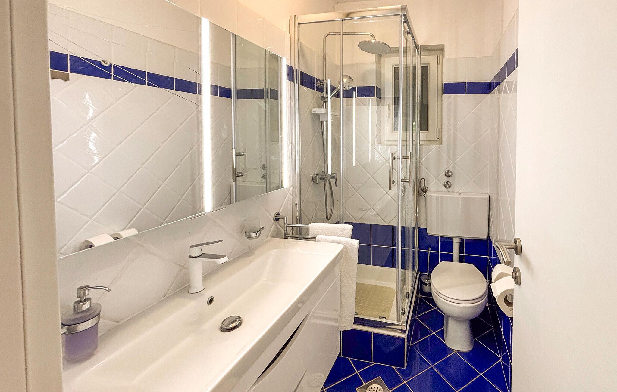 Une salle de bain avec une douche à parois de verre, un lavabo blanc et des toilettes.