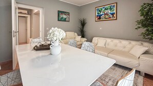 Ett vardagsrum med ett vitt bord, en beige soffa och två tavlor på väggen.