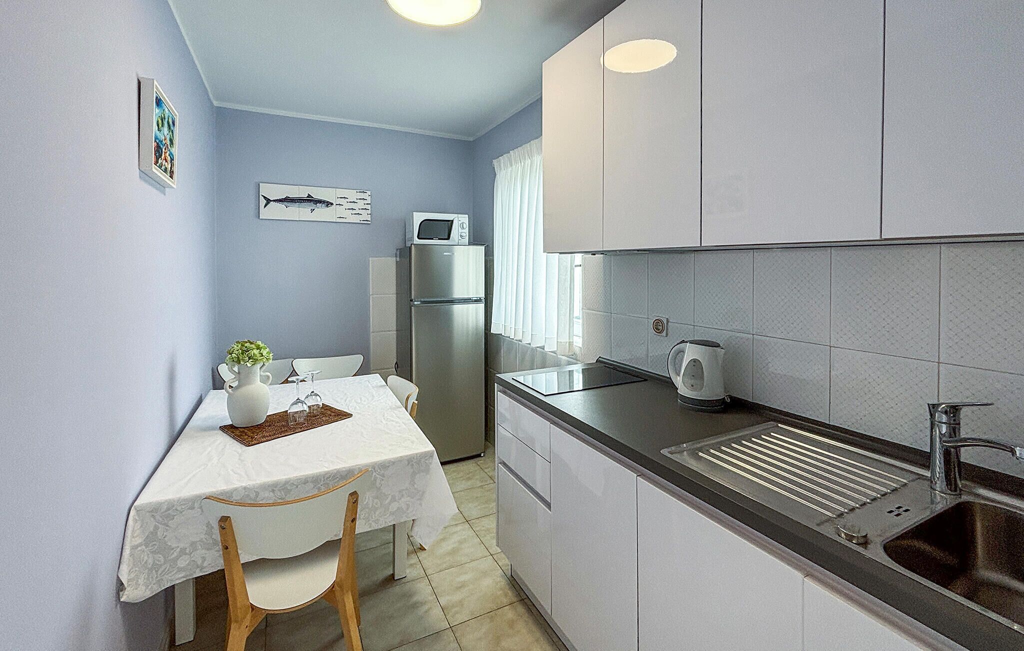 A compact kitchen with a refrigerator, microwave, and sink.