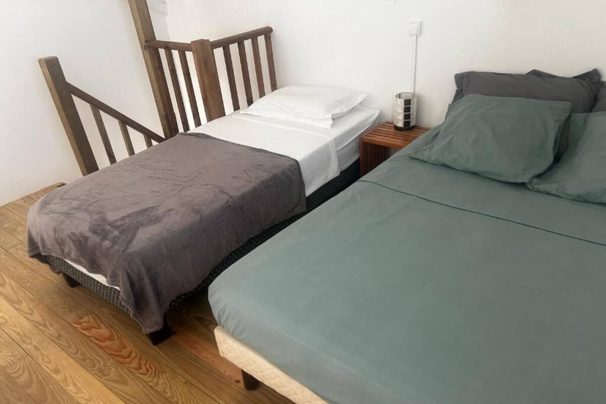 A bedroom with two beds, wooden headboards, a bedside table with a lamp, and a power outlet.