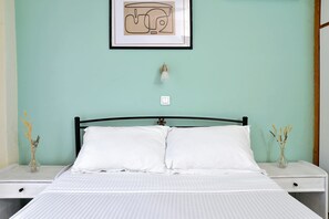 A bed with white bedding, two nightstands with vases, a framed picture above the bed, and a light switch on the wall. - Ilia Edipsos Nest - Homely Vibes and Mountain View (Istiaia-Aidipsos)
