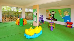 A children's play area with a slide, climbing structures, and colorful wall decorations.
