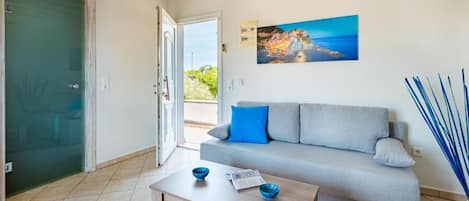 A living room with a sofa, a coffee table, and a painting on the wall.