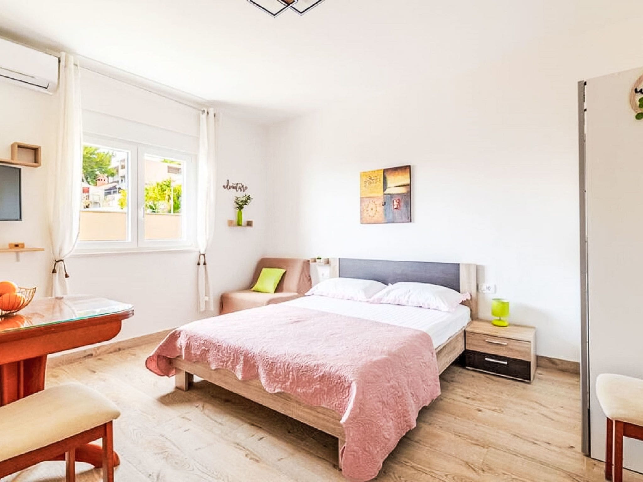 A bedroom with a bed, bedside table, and a window.
