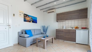 A living room with a grey sofa, a coffee table, and a painting on the wall. - Studios River - Potos Poolside Apartment With View (Thasos)