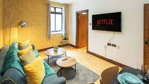 A modern living room with a sofa, coffee table, and a television mounted on the wall. - Central London Apartment 1BR - 5 Min to Hyde Park (London)