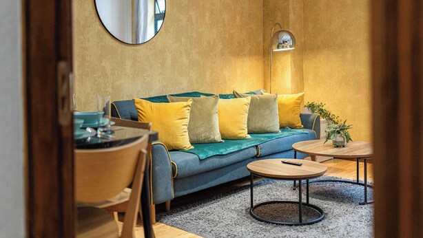 A cozy living room with a sofa, a round coffee table, a dining table, and a mirror on the wall. - Central London Apartment 1BR - 5 Min to Hyde Park (London)