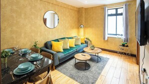A living room with a sofa, coffee table, dining table, and a TV. - Central London Apartment 1BR - 5 Min to Hyde Park (London)