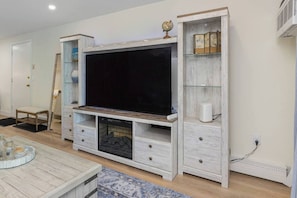 A living room with a large flat-screen TV, wooden cabinets, and a globe on the mantelpiece.