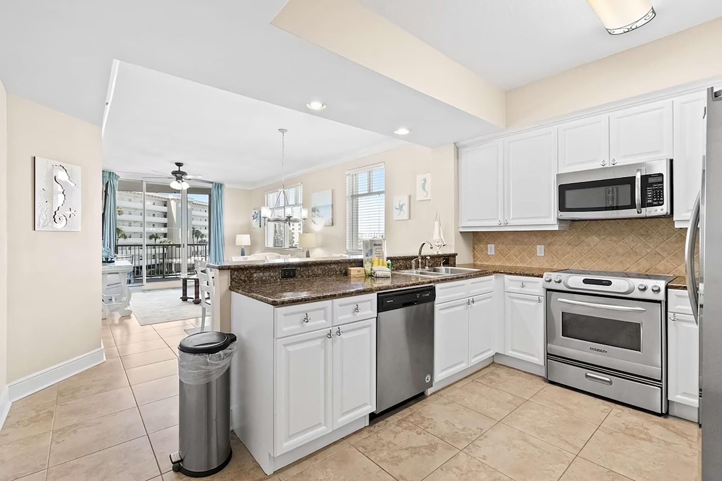 A modern kitchen with white cabinets, a stainless steel dishwasher, a microwave, and an oven.