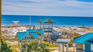 A beachside hotel with multiple blue-roofed structures, a lifeguard tower, and a boardwalk leading to the beach. - Azure #323 (Fort Walton Beach)