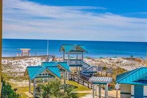 A beachside hotel with multiple blue-roofed structures, a lifeguard tower, and a boardwalk leading to the beach. - Azure #323 (Fort Walton Beach)
