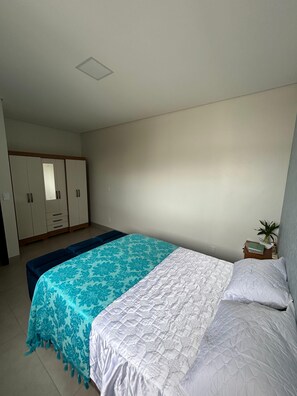 A bedroom with a bed, a nightstand, a wardrobe, and a small plant.