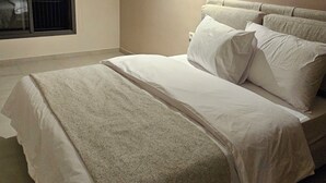 Una camera da letto con un letto, una finestra con persiane e una lampada fissata al muro.