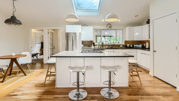 Een moderne keuken met een centraal eiland, hanglampen en een dakraam.
