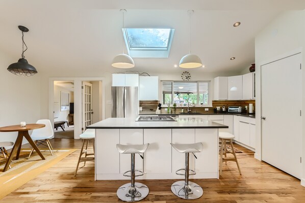 A modern kitchen with a central island, pendant lights, and a skylight. - Bright & Open 2 Bed, Home Walk to Downtown & CU (Boulder)