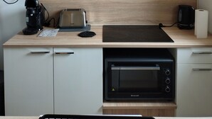 A kitchen with white cabinets, a wooden countertop, a toaster, a coffee maker, a kettle, and a built-in oven. - Holiday rental near La Tranche sur mer (La Jonchère)