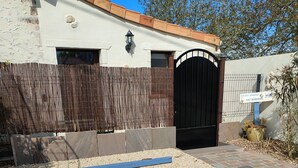 A building with a black gate, a wooden fence, and a gravel driveway. - Holiday rental near La Tranche sur mer (La Jonchère)