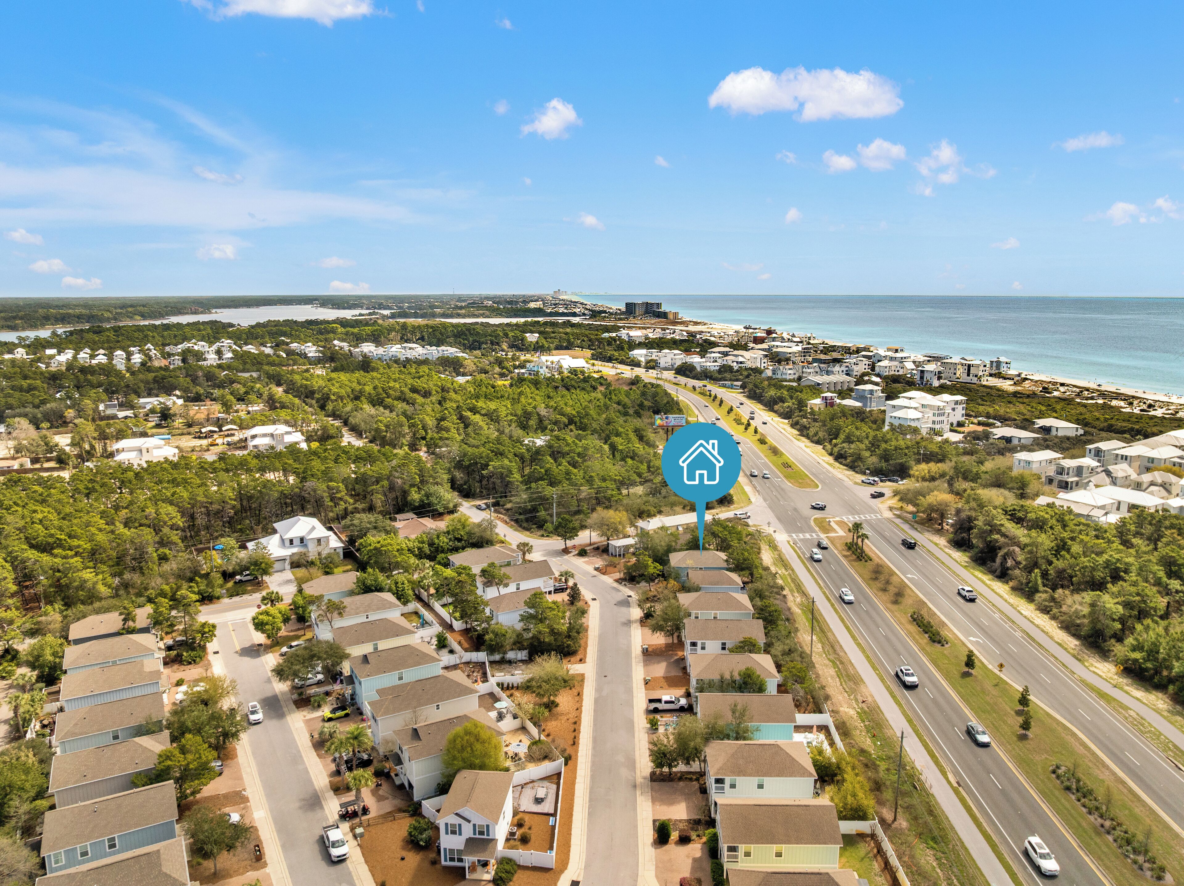 An aerial view of a coastal residential area with houses, roads, and a beach.