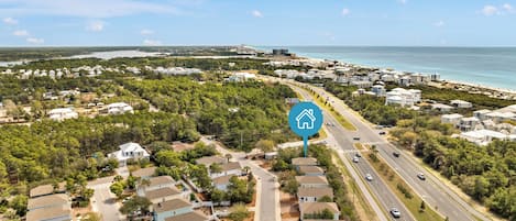 An aerial view of a coastal residential area with houses, roads, and a beach.