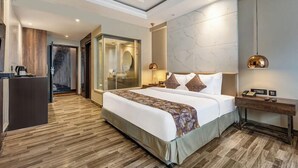 Ein modernes Hotelzimmer mit einem großen Bett, einem Schreibtisch, einer gläsernen Dusche und einer Marmorwand.