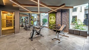 Ein Fitnessstudio mit Trainingsgeräten, einer Ziegelwand und einem Neonzeichen.