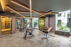 A gym with exercise equipment, a brick wall, and a neon sign. - Sterling Palm Bliss Wellness Resort, Rishikesh (Narendranagar)