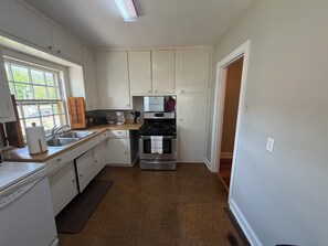A compact kitchen with white cabinets, a stainless steel stove, and a window providing natural light.